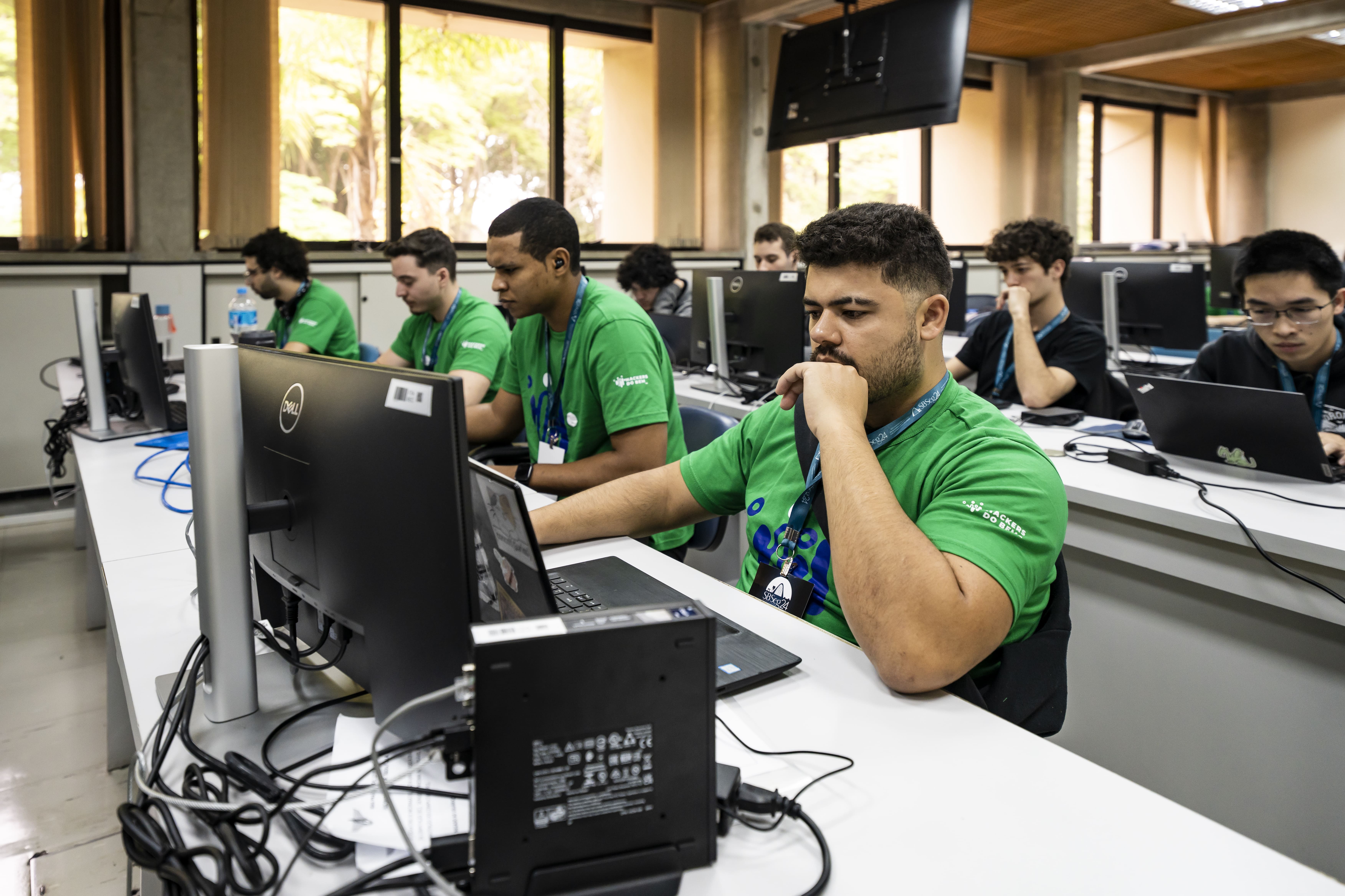 Meninos olhando para o computador concentrados. Há 3 brancos e um negro na imagem.